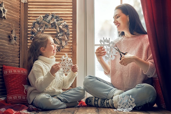 Mama si fiica ce confectioneaza fulgi de nea de hartie