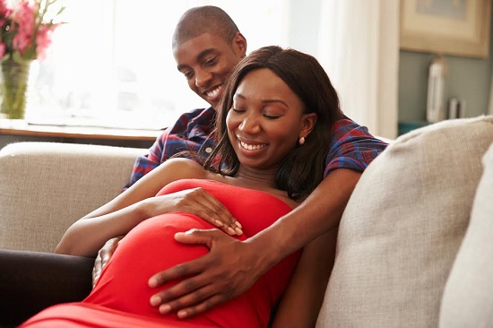 Femeie gravida stand alaturi de partenerul ei