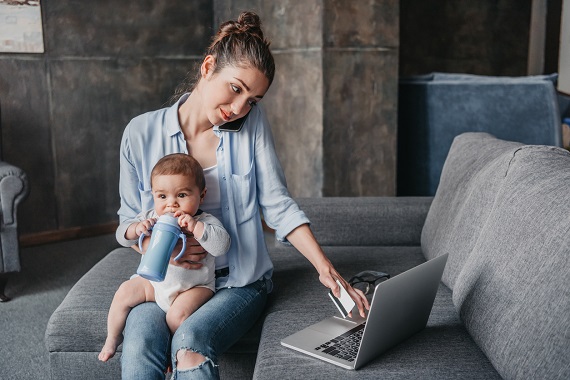 Mama ce isi tine bebelusul in brate si lucreaza la laptop