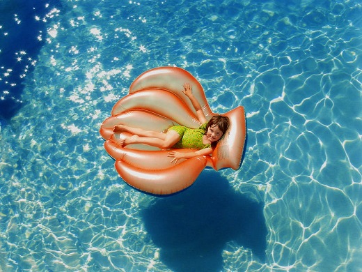 Fetita ce se afla pe o saltea, in piscina