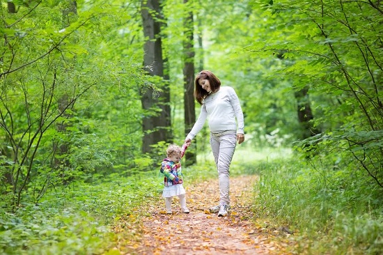 Mama insarcinata la plimbare prin padure, alaturi de fetita ei