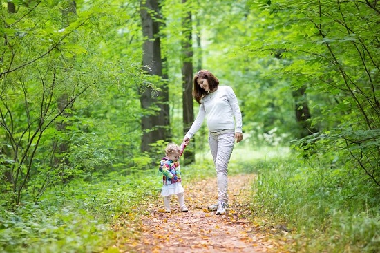 Mama insarcinata la plimbare prin padure, alaturi de fetita ei