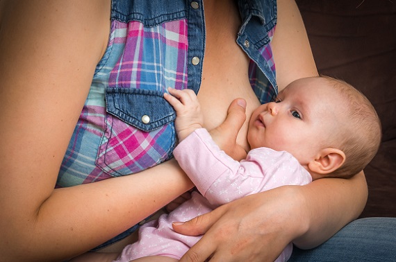 Mama ce incearca sa-i dea bebelusului sa suga de la un singur san