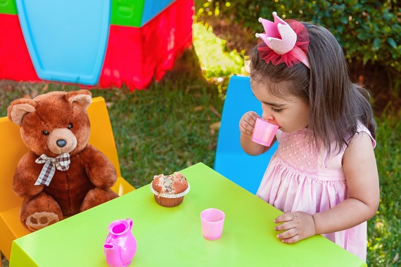 Fetita ce se joaca in gradina de-a „Tea party”