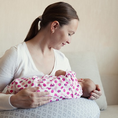 Mama ce alapteaza cu ajutorul unei perne de alaptare