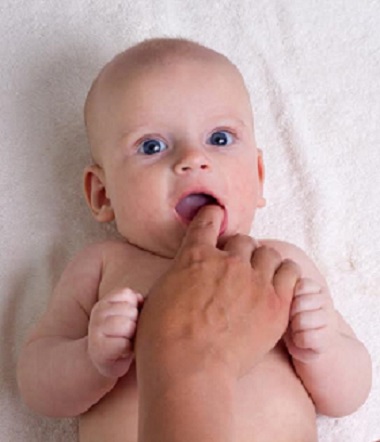 Bebelus caruia i se face un masaj al gingiilor