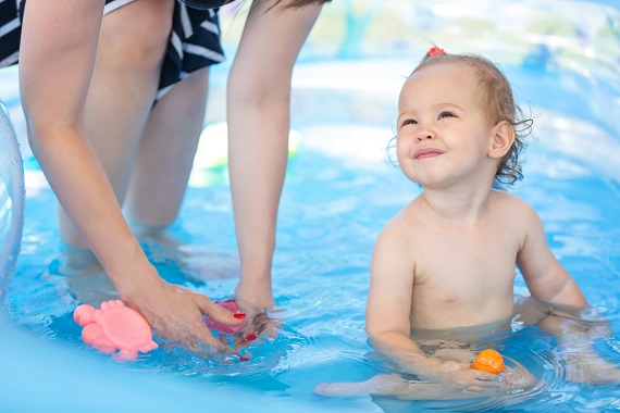 Mama ce se joaca cu bebelusul din piscina gonflabila