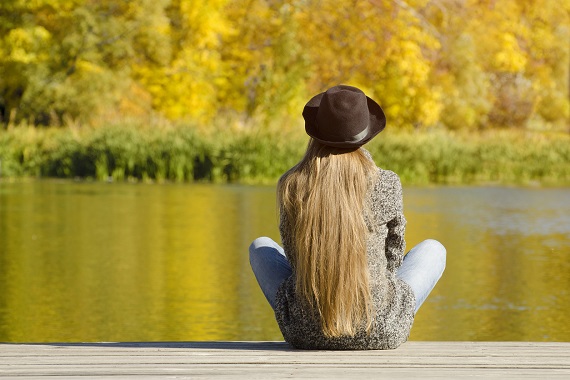 Fata cu palarie, ce sta la soare pe malul unui lac