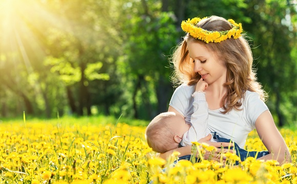 Mama cese afla pe un camp de flori si isi alapteaza bebelusul