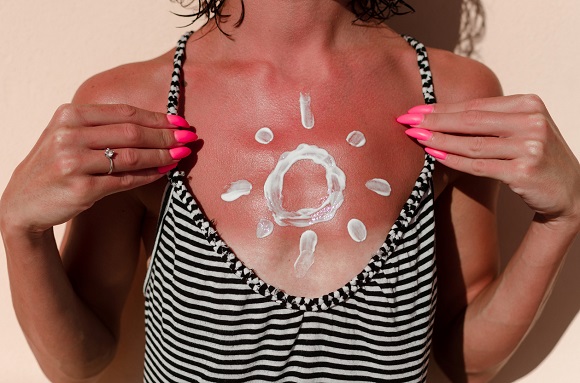 Femeie ce aplica protectie solara pe piept