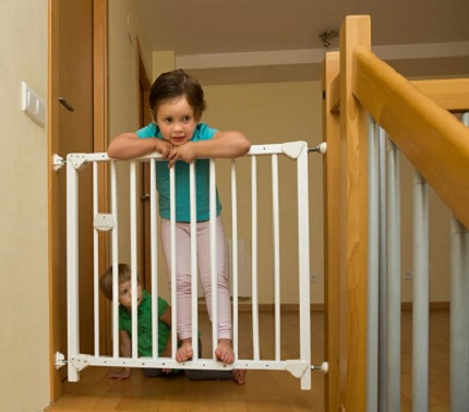 Fetita ce s-a catarat pe usita de protectie de la scarile din casa