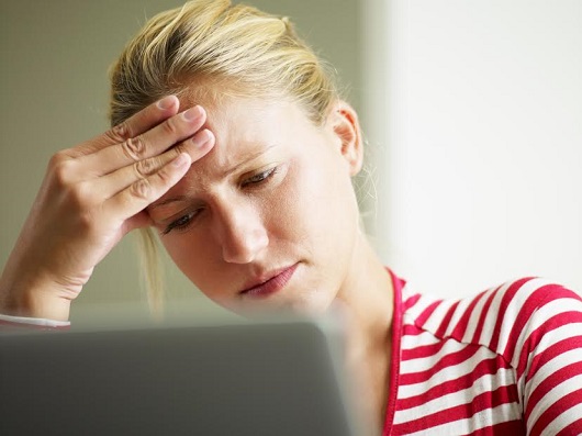 Femeie pe care o doare capul si sta in fata laptopului
