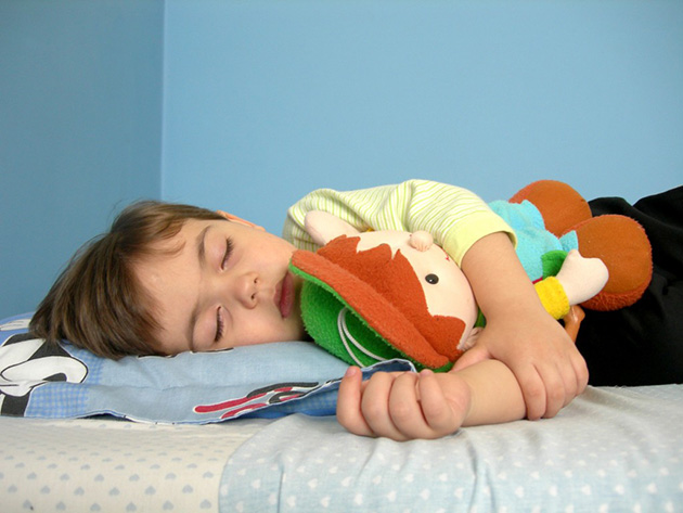 Copil doarme cu jucarie in brate