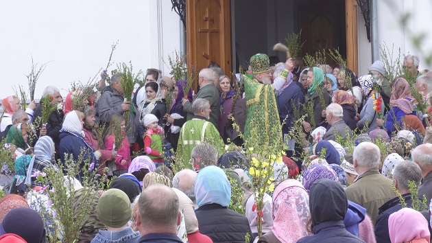 credinciosi-cu-ramuri-de-salcie-si-preot-la-intrarea-intr-o-biserica