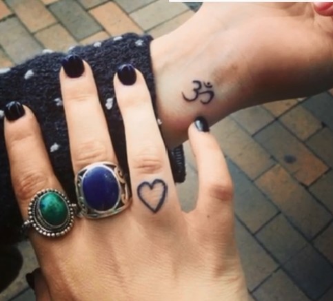 tatuaj-cu-simbolul-OM-si-cu-inima-pe-mana-cu-inele-a-unei-femei