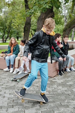 baietel-ce-se-da-pe-skateboard-si-este-imbracat-cu-geaca-din-piele-si-pantaloni-bleu