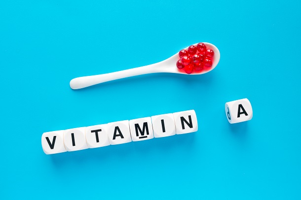 capsule-gelatinoase-rosii-intr-o-lingurita-si-cuvantul-vitamina-A-scris-din-cuburi-albe