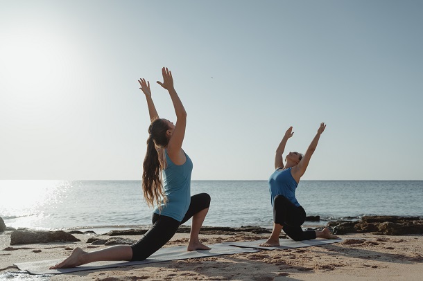 doua-femei-care-fac-exercitii-tip-yoga-la-malul-marii