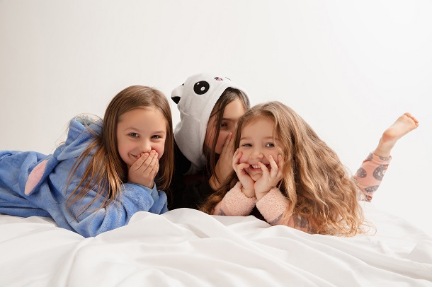 trei-fetite-imbracate-in-pijamale-distrandu-se-in-timp-ce-stau-in-pat