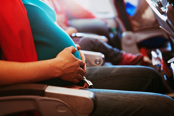 femeie-insarcinata-stand-pe-scaun-in-avion-si-atingandu-si-cu-mainile-burtica-de-gravida