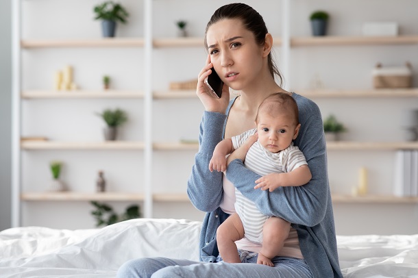 mama-ingrijorata-care-isi-tine-in-brate-bebelusul-in-timp-ce-vorbeste-la-telefon