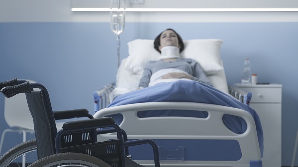 femeie-aflata-pe-patul-de-spital-in-fata-patului-aflandu-se-un-scaun-cu-rotile