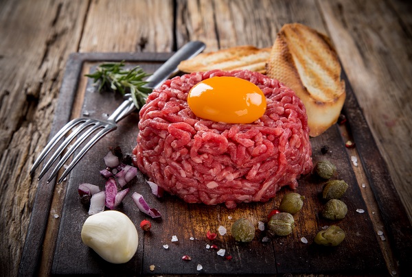 beef-tartar-pe-farfurie-servit-cu-ou-crud-pe-deasupra-si-cu-felii-de-pâine-prajita