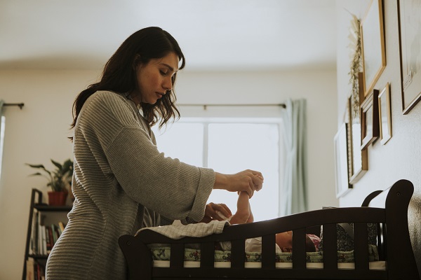 mama-care-schimba-scutecul-unui-nou-nascut-aflat-in-patutul-sau