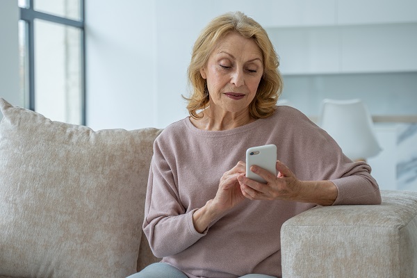 femeie-in-vârsta-care-sta-pe-o-canapea-in-timp-ce-manipuleaza-telefonul-mobil