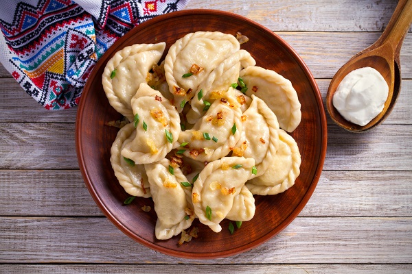 pierogi-aflate-pe-o-farfurie-rustica-si-avand-alaturi-de-ele-o-lingura-de-lemn-cu-smantana