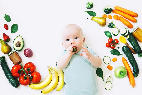 bebelus-care-vrea-sa-manance-o-capsuna-si-este-inconjurat-de-diverse-legume-fructe-si-piureuri-de-fructe-sau-de-legume