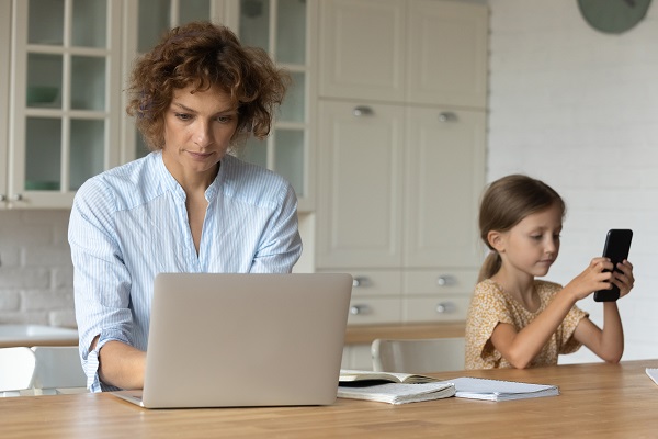 mama-ce-lucreaza-pe-laptop-in-timp-ce-fetita-ei-isi-ocupa-timpul-cu-telefonul