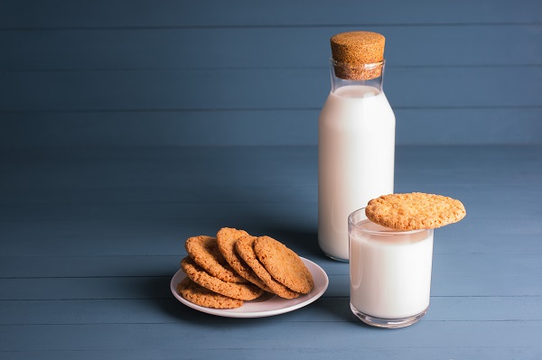 biscuiti de casa pe o farfurioara si un biscuite asezat pe un pahar cu lapte