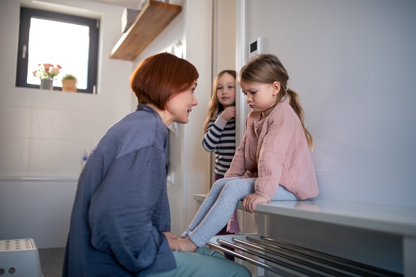 mama care incearca sa discute cu fetita ei care sta trista in baie