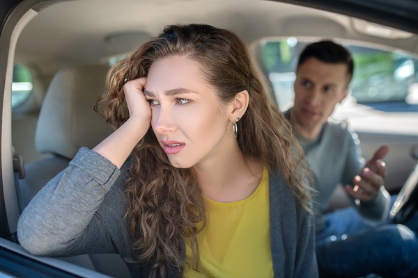 femeie trista in masina in timp ce sotul ei continua sa vorbeasca