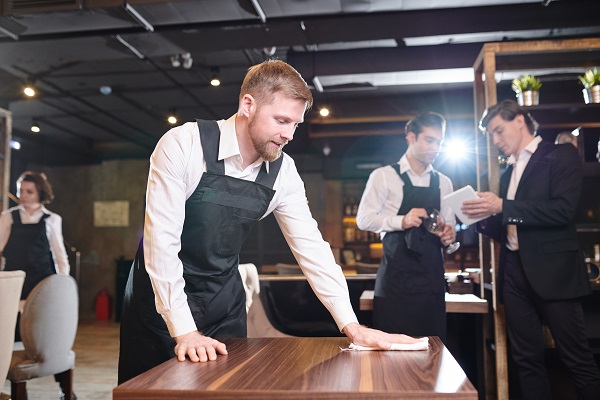 ospatar tanar cu barba incercand sa stearga o masa din restaurant 