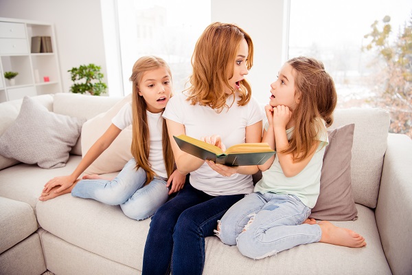 mama si cele doua fetite ale ei stau pe canapea si sunt uimite de ceea ce au citit dintr-o carte