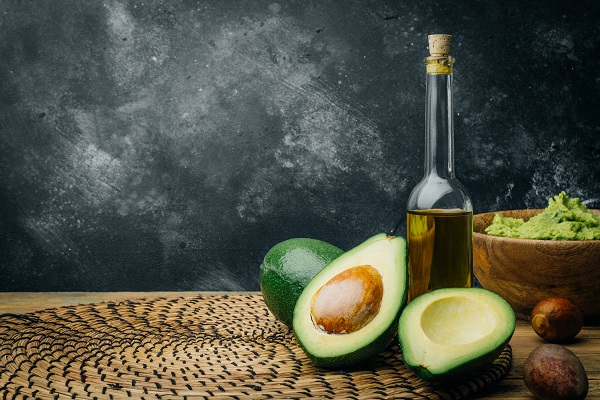 fructe proaspete de avocado sâmburi de avocado ulei de avocado in sticla si guacamole intr-un castronel de lemn