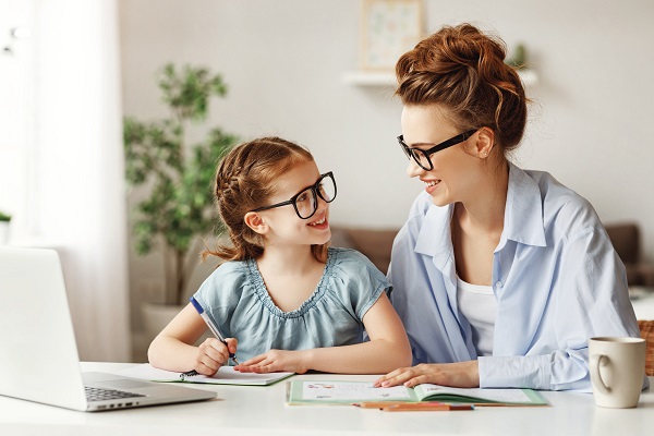 mama si fetita care poarta ochelari si stau amandoua la birou ca fetita sa-si faca temele