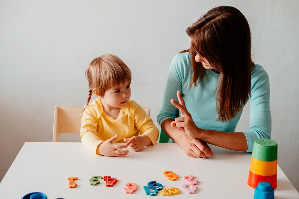 mama care sta alaturi de fetita ei la o masa si o ajuta sa invete sa numere