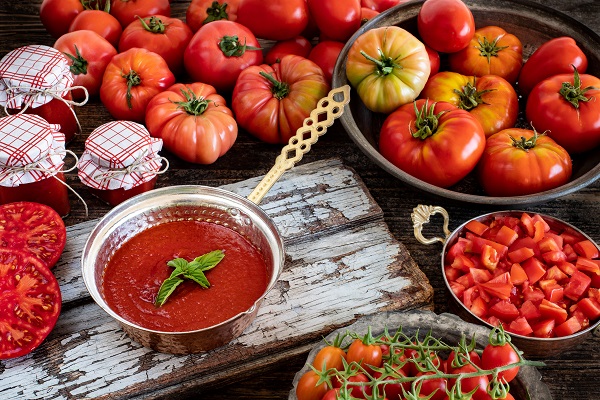 rosii, pasta de tomate in borcane si pasta de tomate ornata cu busuioc intr-un castron de inox