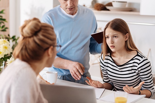 adolescenta stand in fata laptop-ului si avand o confruntare cu parintii ei