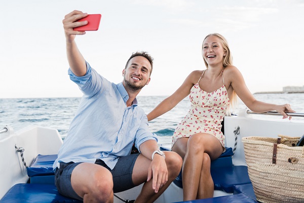 femeie tanara si un barbat tanar veseli facandu-si selfie la bordul unui iaht