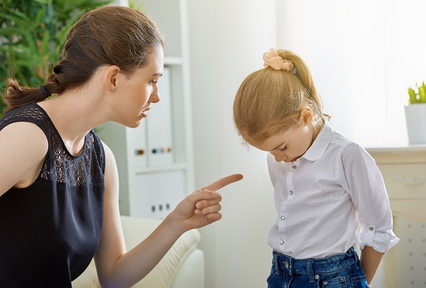 mama furioasa imbracata in negru mustrandu-si fetita care si-a lasat capul in jos de rusine