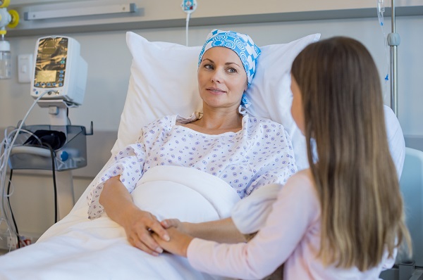 fetita care o tine de mana pe mama ei bolnava de cancer, aflata pe patul de spital