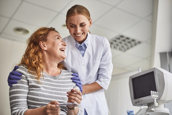 doctorita alaturi de o femeie de varsta mijlocie entuziasmata ca este insarcinata