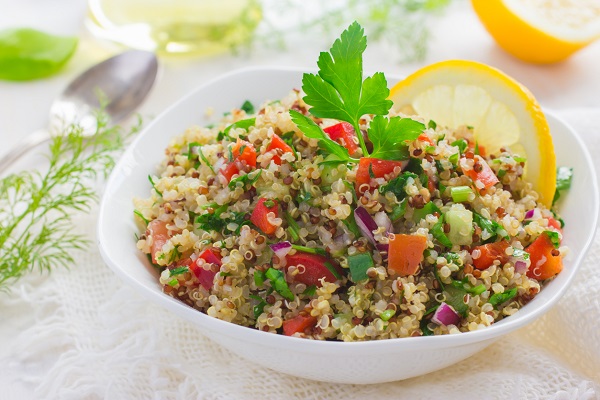 salata cu quinoa, rosii, castraveti, ceapa rosie si cu o felie de lamaie