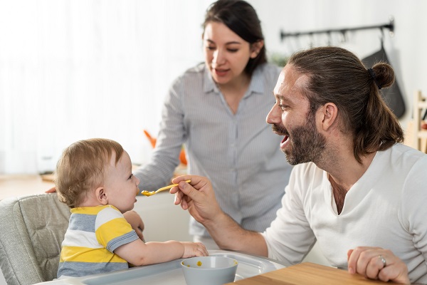 mama care isi supravegheaza sotul in timp ce acesta hraneste bebelusul