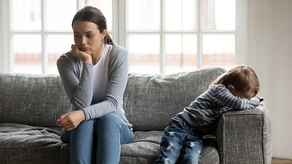 mama deprimata ce sta pe canapea, iar la celalalt capat al canapelei se afla baietelul ei, care este foarte trist