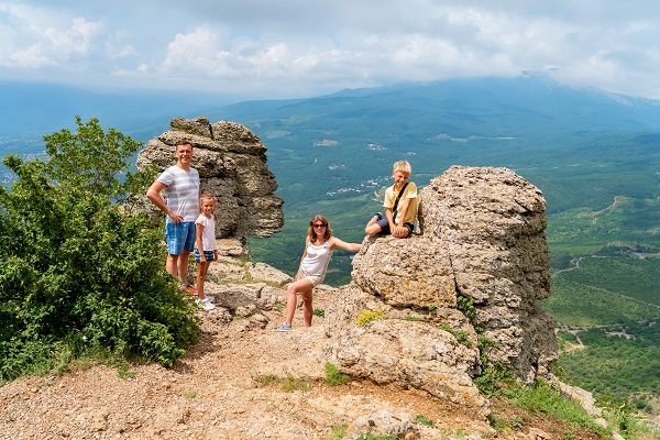 parinti si cei doi copii ai lor fericiti ca au ajuns la destinatie intr-o drumetie pe munte